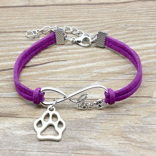 Purple bracelet with silver paw charm and 'love' inscription on a wooden surface