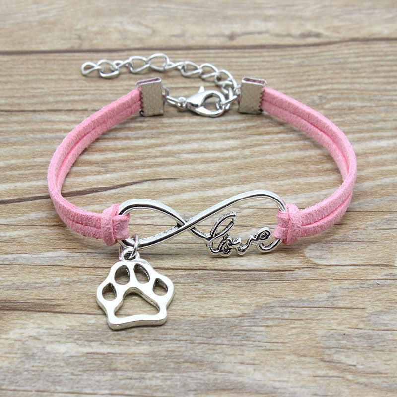 Pink bracelet with silver paw charm and 'love' infinity symbol on a wooden surface