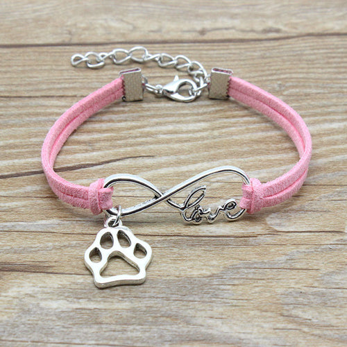 Pink bracelet with silver infinity charm and paw print on a wooden surface