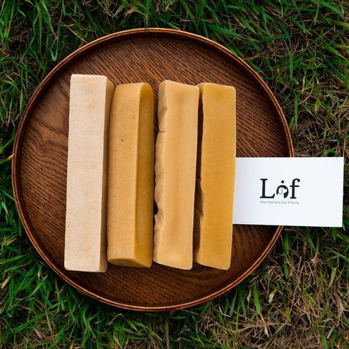 Four bars of soap on a wooden plate with a 'Laf' card on grass