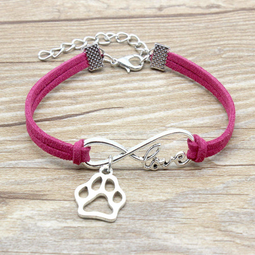Pink bracelet with silver paw charm and 'love' inscription on a wooden surface