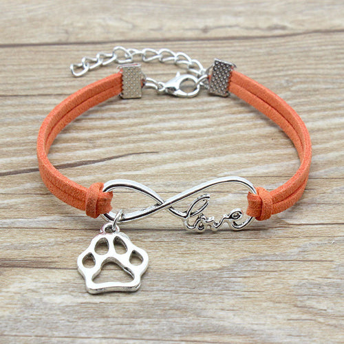 Orange bracelet with silver paw charm and infinity symbol on a wooden surface