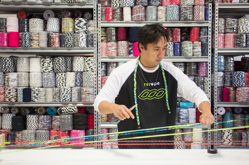 Man working with colorful ribbons in a store filled with spools of ribbon.