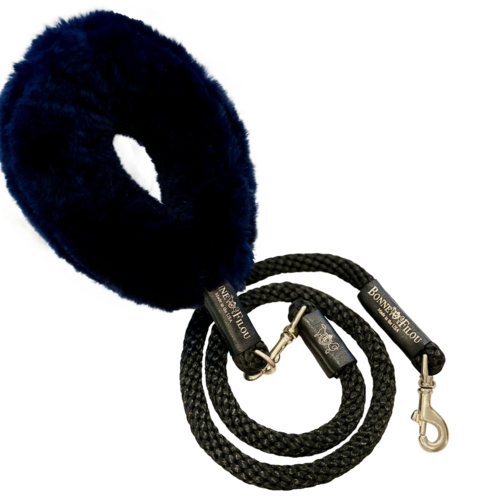 Navy blue fluffy dog toy with a black rope leash on a white background