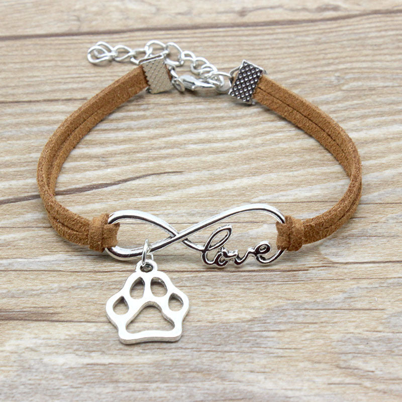 Bracelet with paw charm and 'love' infinity symbol on a wooden surface