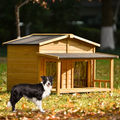 Dog standing in front of a wooden doghouse in a grassy area with trees in the background