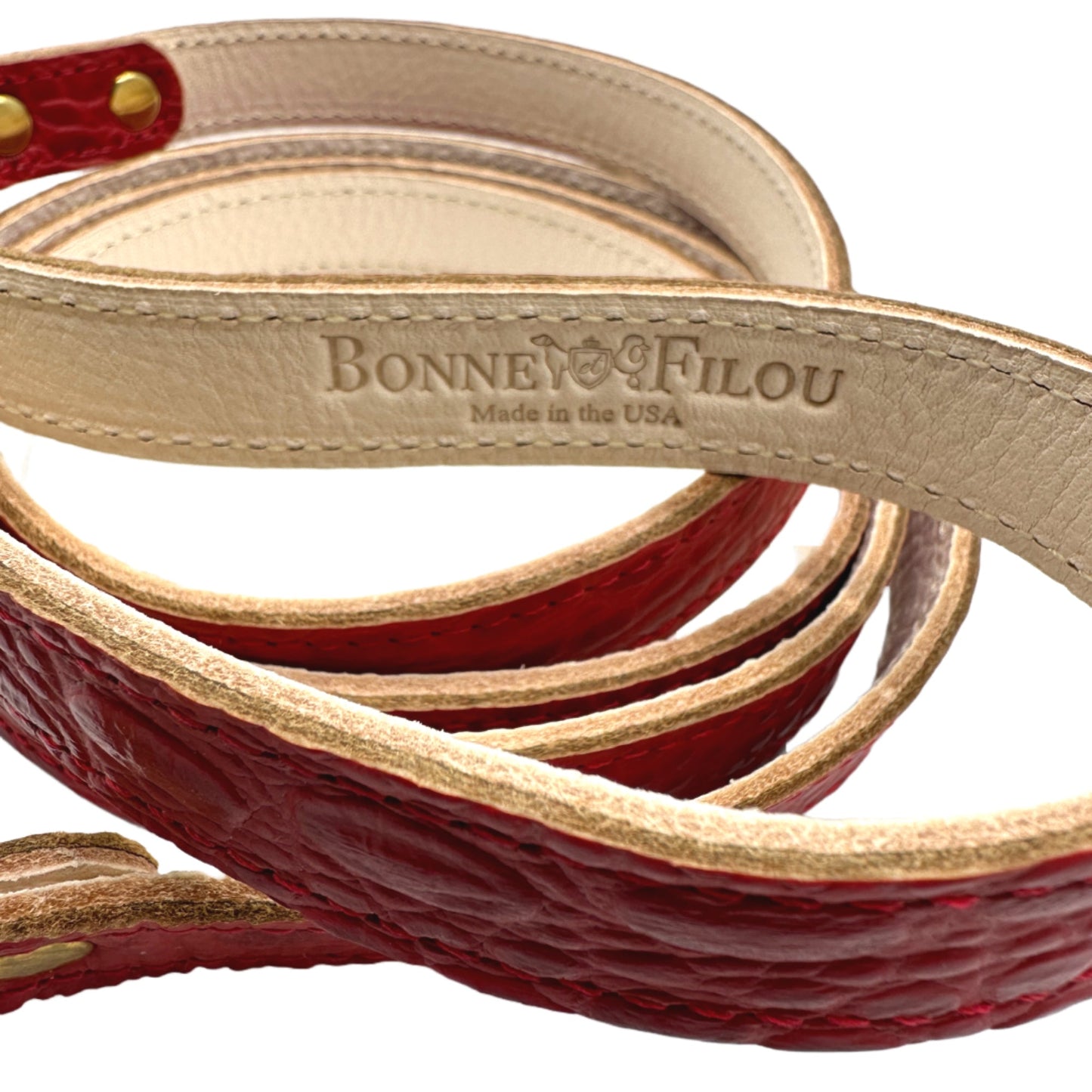 Coiled red and beige leather dog leash with 'Bonnie & Filou' branding on a white background