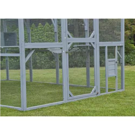 Large outdoor bird cage with mesh sides on a grassy area