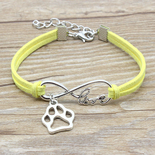 Yellow bracelet with silver paw charm and 'love' inscription on a wooden surface