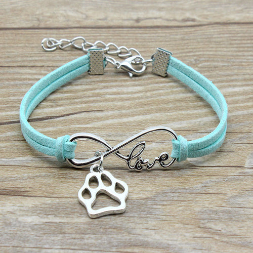Turquoise bracelet with silver paw charm and 'love' infinity symbol on a wooden surface