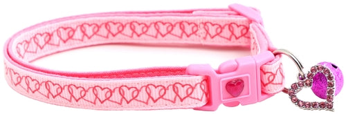 Pink dog collar with heart patterns and a bell charm on a white background