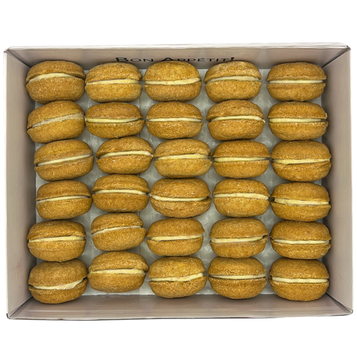 Box of pumpkin spice macarons with cream filling on a white background