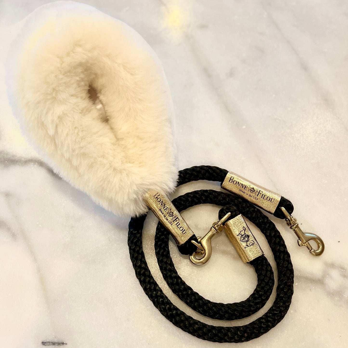Black dog leash with fluffy white handle on a marble surface