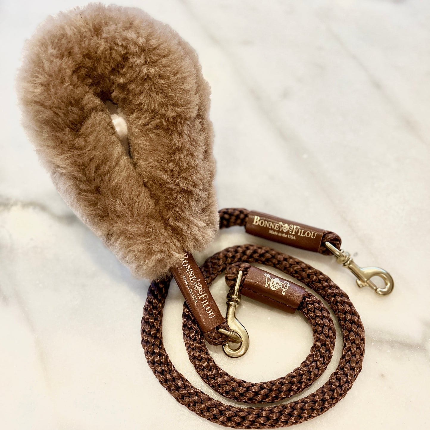 Brown braided dog leash with fluffy brown handle on a white background