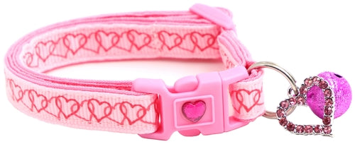 Pink dog collar with heart patterns and a matching bell on a white background