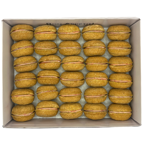 Box of yellow macarons with pink filling on a white background