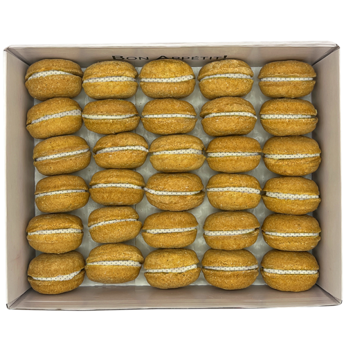 Box of pumpkin spice macarons with white filling on a white background