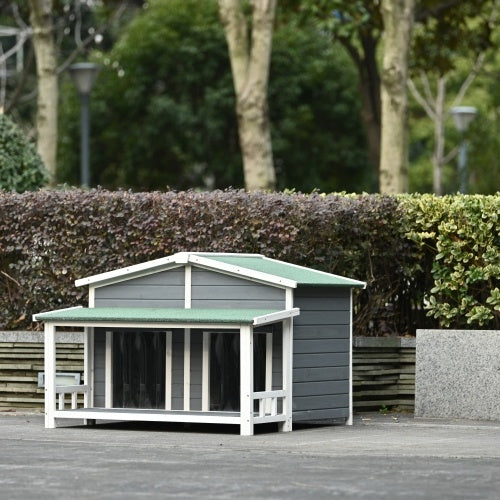 Gray outdoor dog house with green roof in a garden setting