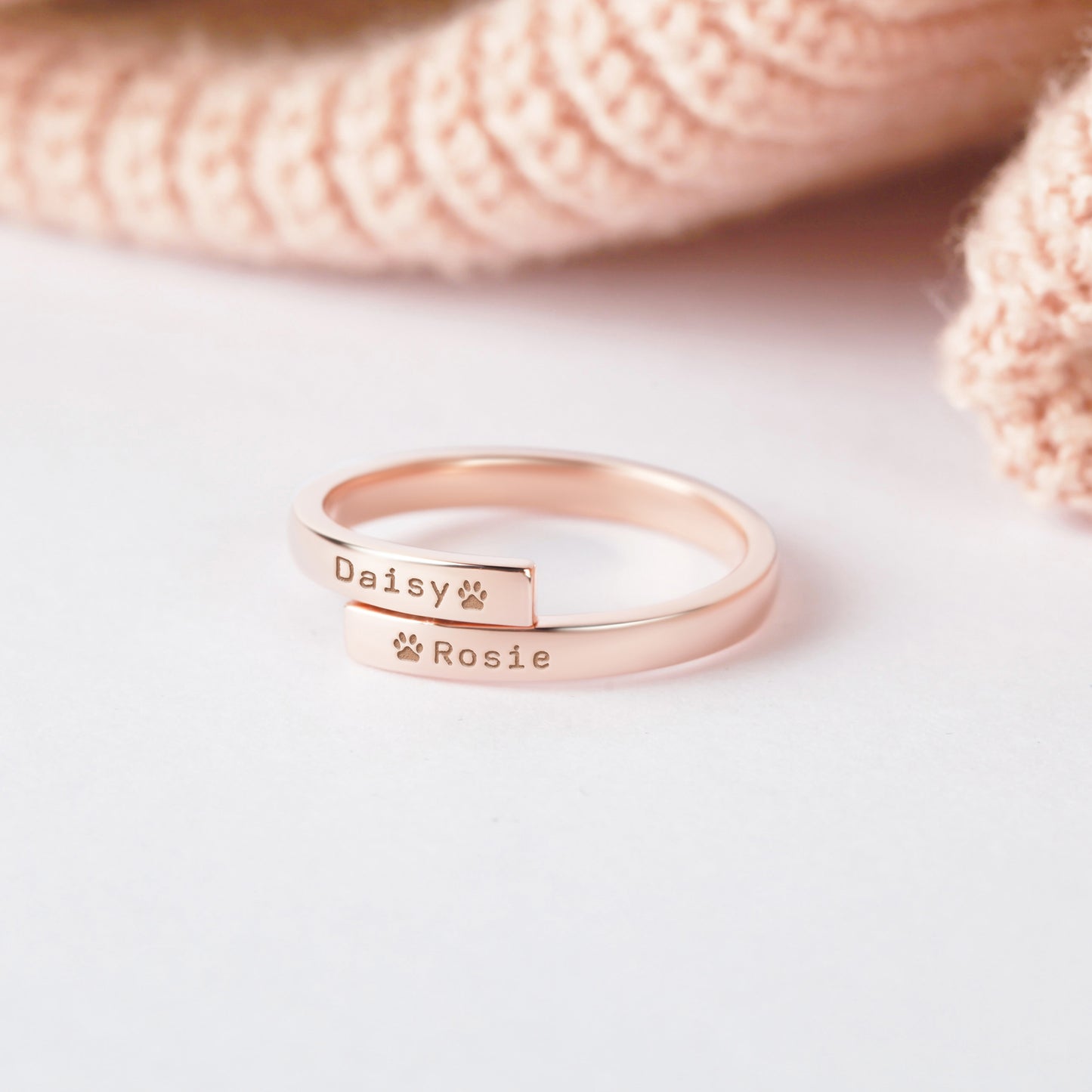 Rose gold ring with engraved names on a light background