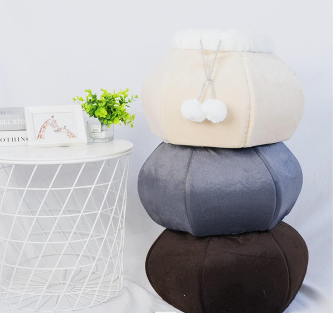 Stack of three round cushions in beige, gray, and brown on a white surface with a small plant and books in the background.