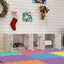 White pet playpen with open doors on a colorful floor, decorated with Christmas stockings and artwork.
