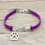 Purple bracelet with silver paw charm and 'love' inscription on a wooden surface