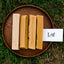 Four bars of soap on a wooden plate with a 'Laf' card on grass