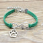 Green bracelet with silver infinity and paw charm on a wooden surface