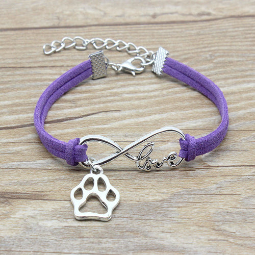 Purple bracelet with silver paw charm and 'love' infinity symbol on a wooden surface