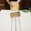 Person holding a wooden loom with colorful strings on a white surface