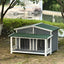 Dog house with green roof and gray body in a garden setting