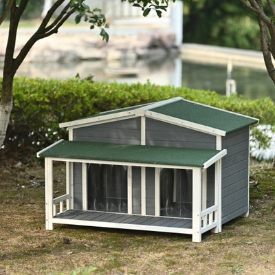 Dog house with green roof and gray body in a garden setting