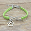 Green bracelet with silver paw charm and 'love' infinity symbol on a wooden surface