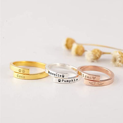 Three gold, silver, and rose gold rings with engraved names on a light background.