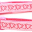 Pink dog collar with heart patterns and a keychain on a white background
