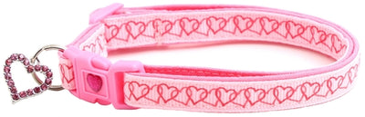 Pink dog collar with heart patterns and a keychain on a white background
