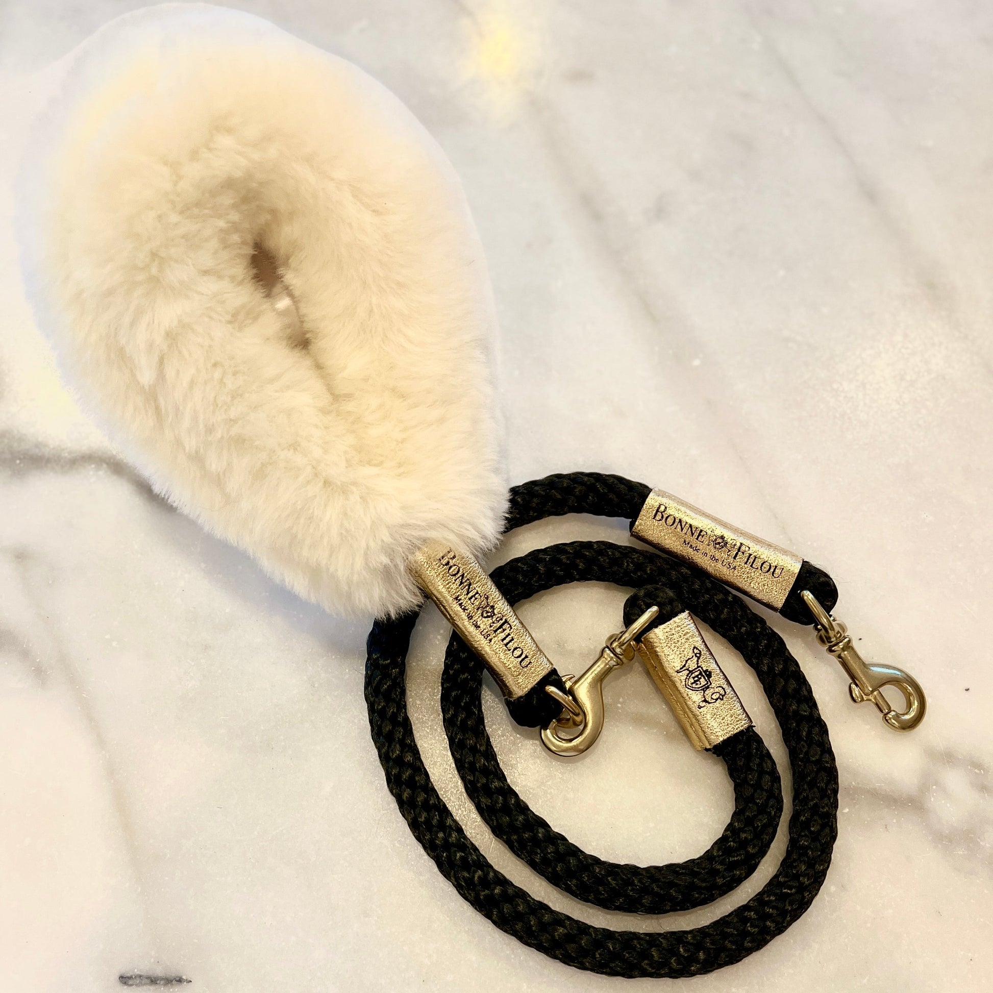 Black dog leash with fluffy white handle on a marble surface