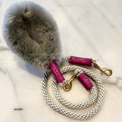 Dog leash with fur handle and pink clips on a white background