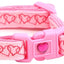 Pink dog collar with heart patterns and a bell on a white background