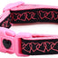Pink and black dog collar with heart design and keychain on a white background