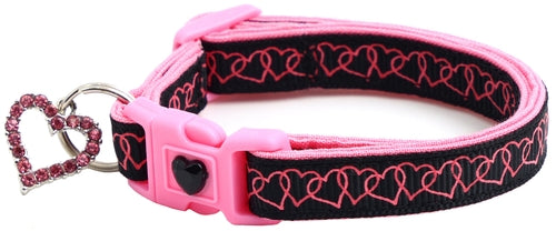 Pink and black dog collar with heart design and keychain on a white background