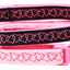 Pink and black dog collar with heart patterns and a bell on a white background