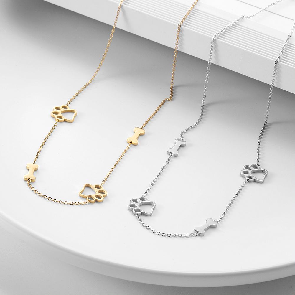 Two gold and silver paw print necklaces on a white surface.