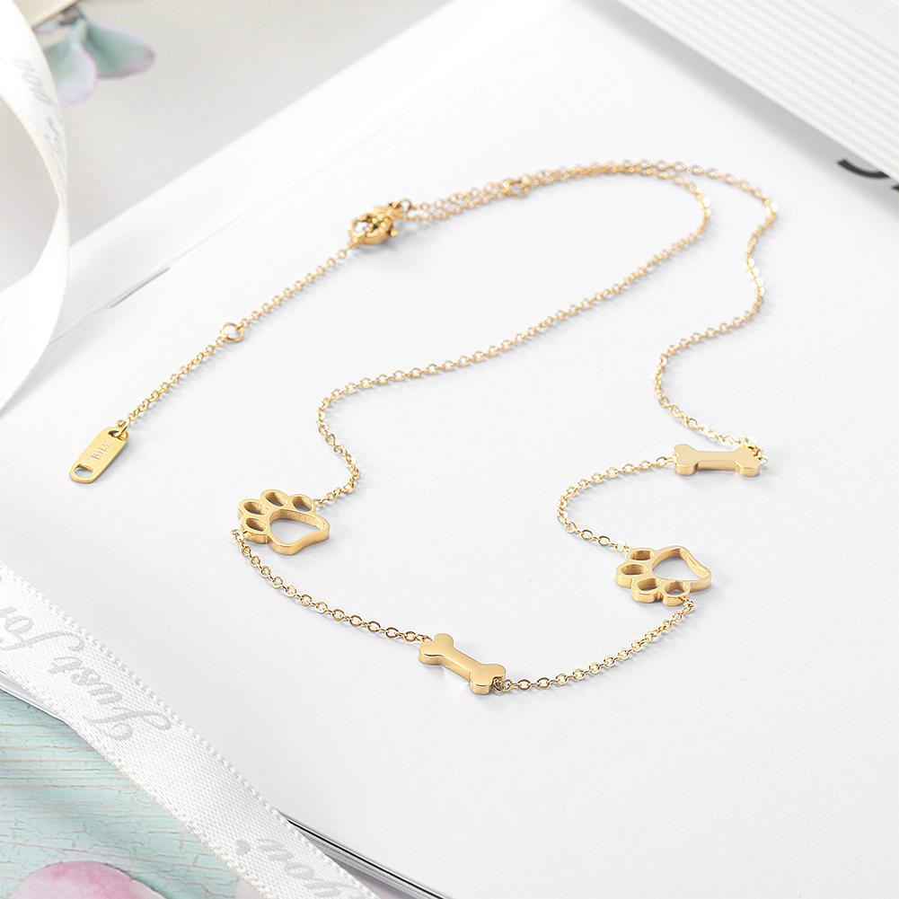 Gold necklace with paw and cross charms on a white background
