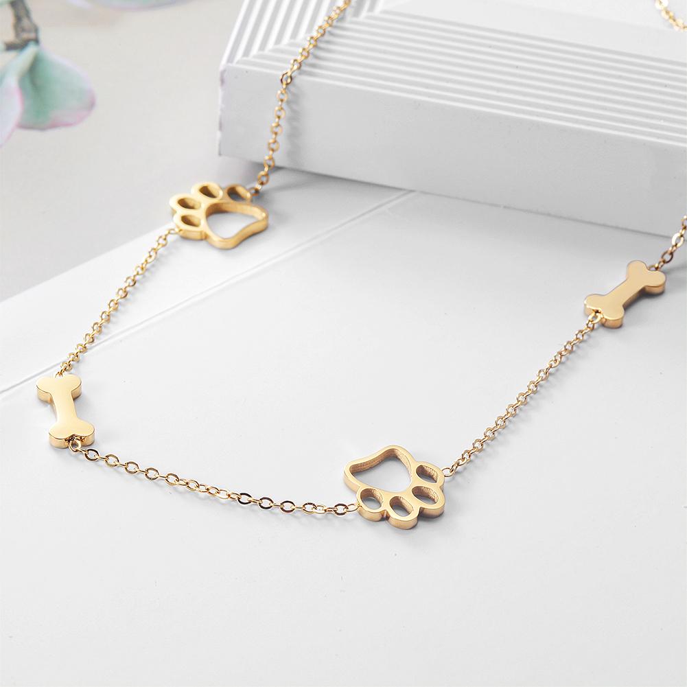 Gold necklace with paw and bone designs on a white surface