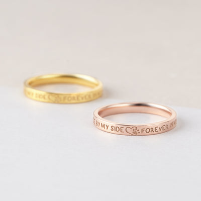 Two gold rings with engraved text on a light gray background