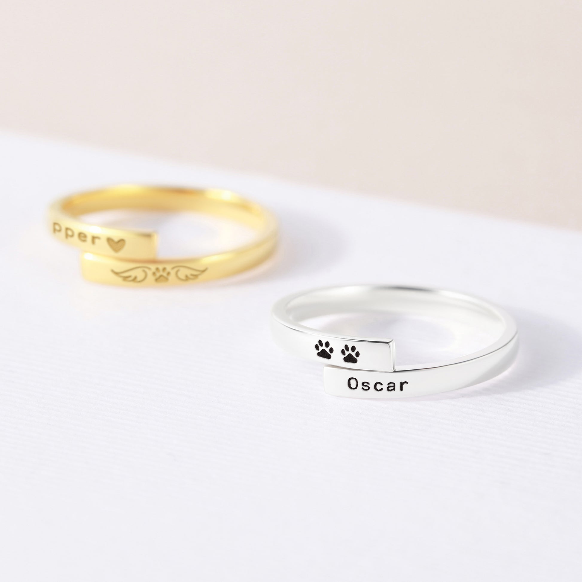 Gold and silver rings with paw prints and names on a white background