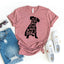 Pink t-shirt with dog graphic and text, paired with denim shorts and white sneakers on a white background