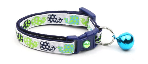 Dog collar with green paw print pattern and blue bell on a white background